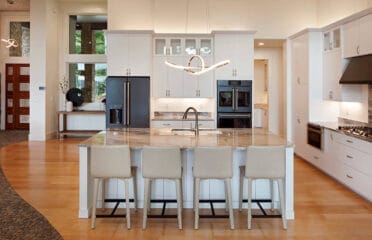 Modern kitchen with marble island, white cabinets and wood floors